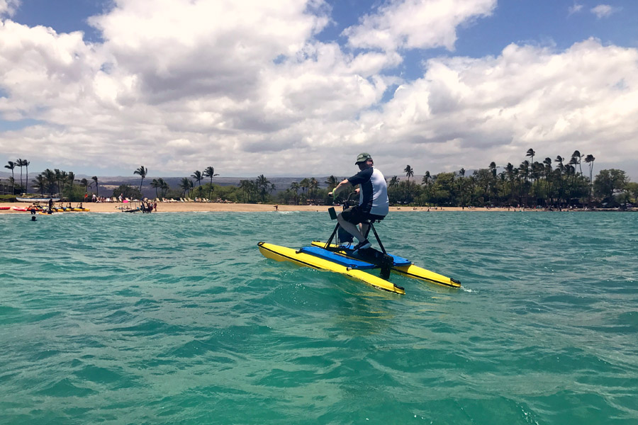 Cookies & Clogs | Oceans Sports Aloha Days offer 4 hours of unlimited water sports beach equipment including kayaks, stand-up paddleboards, snorkel gear, and rides on the glass bottom boat. One of the many things to do on the Big Island of Hawaii with kids. Man on hydro bike.